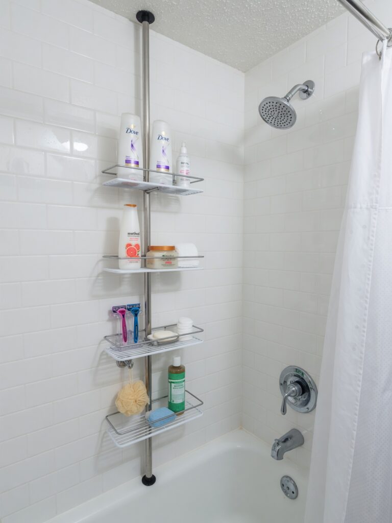 Tension shower caddy in rental apartment bathroom providing damage-free 
storage without drilling or wall mounting